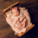 Beautiful Newborn baby girl posed in a wooden crib by newborn photographer in Norfolk