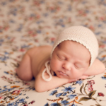 Beautiful Newborn baby girl laying on a floral blanket by newborn photographer in Norfolk