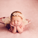 Beautiful Newborn baby girl sitting with her chin on her hands by newborn photographer in Norfolk