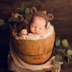 Beautiful Newborn baby boy posed in a bucket wearing a bear bonnet by newborn photographer in Norfolk