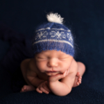 Beautiful Newborn baby boy wearing blue bobble hat by newborn photographer in Norfolk
