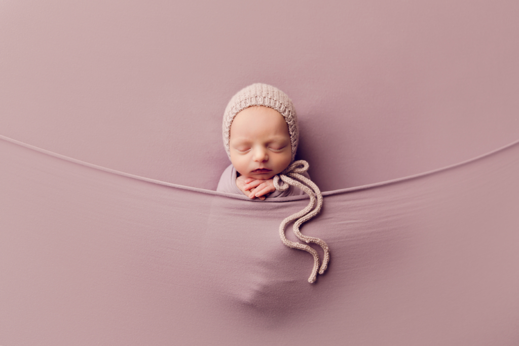 newborn baby wrapped in lilac with bonnet by newborn photographer norfolk