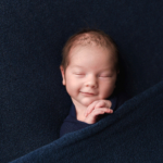 newborn baby boy in navy with a smile newborn photographer norfolk