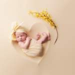 Beautiful Newborn baby girl posed in a heart bowl wearing a yellow bow by newborn photographer in Norfolk