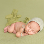 newborn baby boy wearing a green bonnet by newborn photographer norfolk