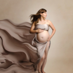 pregnant woman wearing cream satin on a cream background by maternity photographer norfolk